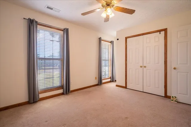 an empty room with windows and fan