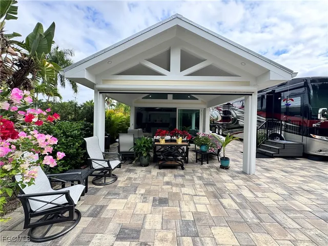 a view of a patio with furniture and flowers in front of house
