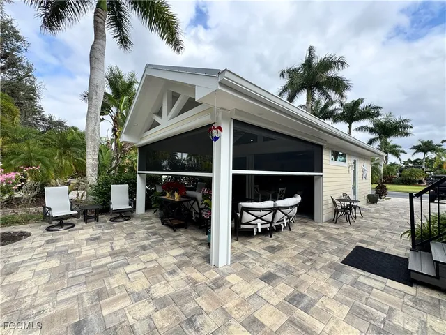 a view of a patio with table and chairs potted plants and floor to ceiling window