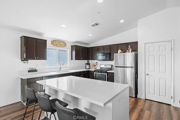a kitchen with stainless steel appliances a kitchen island hardwood floor sink and stove
