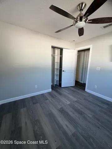 an empty room with wooden floor and a ceiling fan