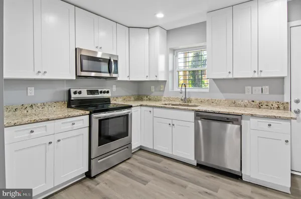 a kitchen with granite countertop white cabinets white stainless steel appliances and sink