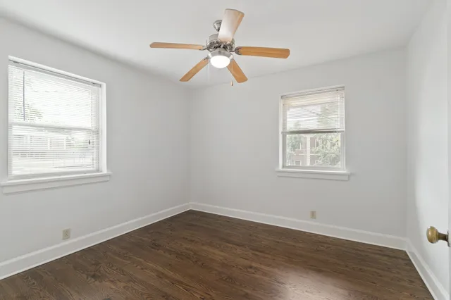 a view of a room with wooden floor ceiling fan and window