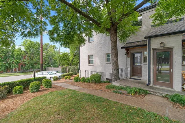 a front view of a house with garden and trees