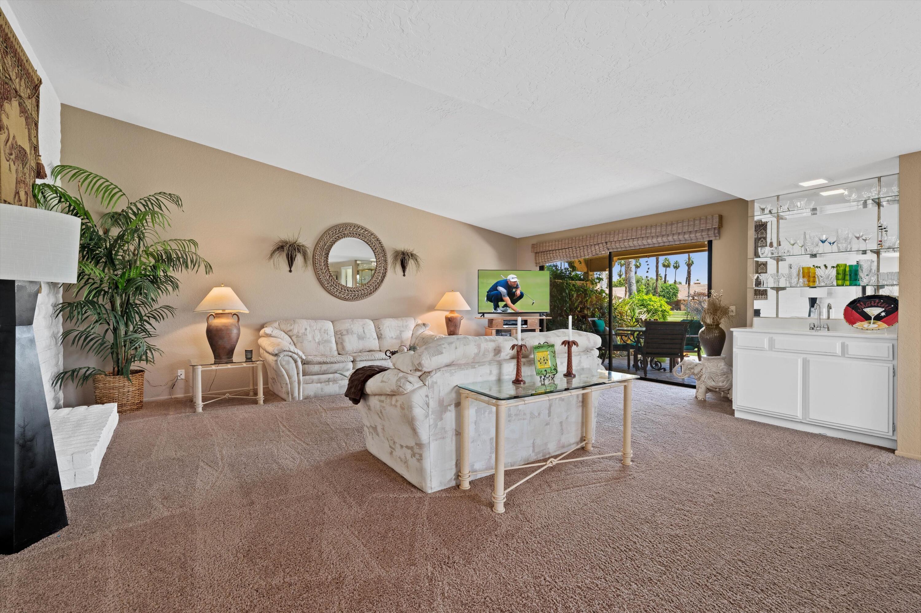 56 Maximo Way Palm Desert, CA 92260 - Photo 19 of 29 a living room with furniture a fireplace a potted plant and a large window