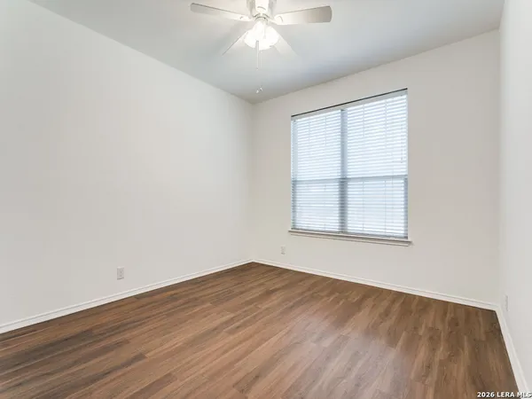 an empty room with wooden floor chandelier fan and windows