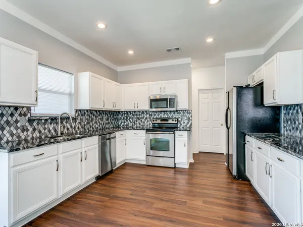 a kitchen with granite countertop white cabinets and stainless steel appliances