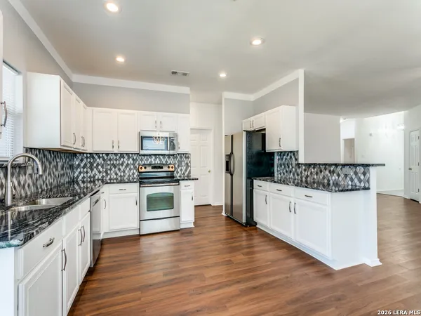 a kitchen with stainless steel appliances granite countertop a stove top oven a sink and a refrigerator