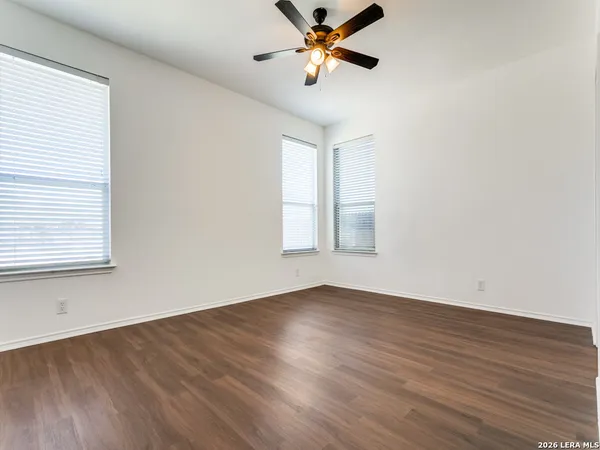 a view of empty room with wooden floor and fan