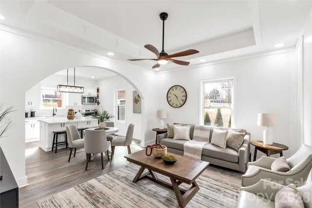 a living room with furniture a clock on wall and a window