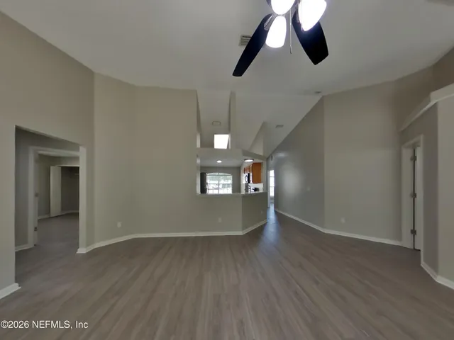 a view of an empty room with window and wooden floor