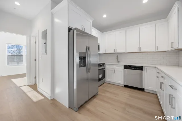 a large kitchen with stainless steel appliances granite countertop a stove a sink and white cabinets