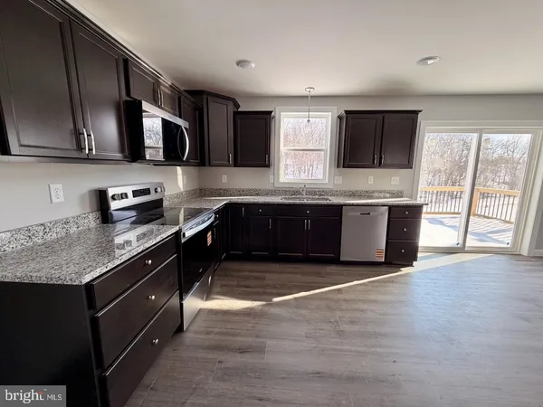 a large kitchen with stainless steel appliances granite countertop a sink and cabinets