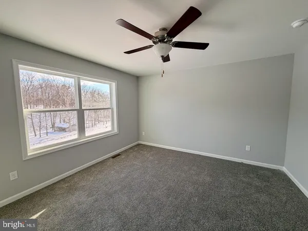 an empty room with ceiling fan and windows