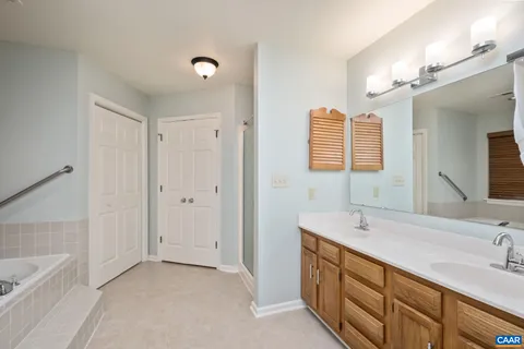 a bathroom with a double vanity sink a large mirror and a bathtub