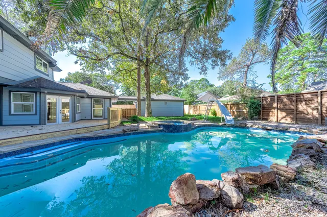 a backyard of a house with table and chairs plants and large tree