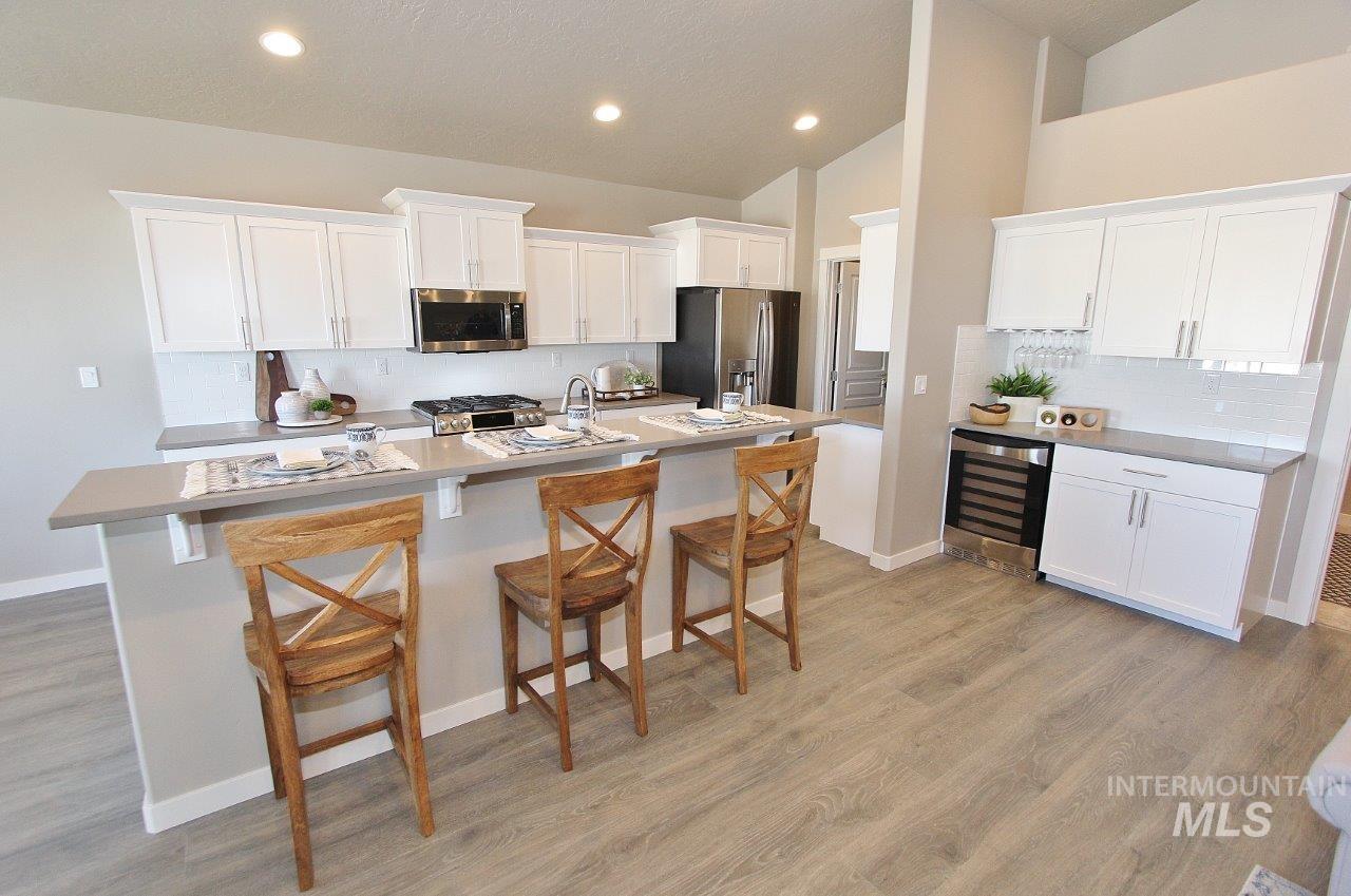 3553 North Eleanor Way Star, ID 83669 - Photo 2 of 20 Kitchen with white cabinets, a breakfast bar, appliances with stainless steel finishes, vaulted ceiling, and recessed lighting