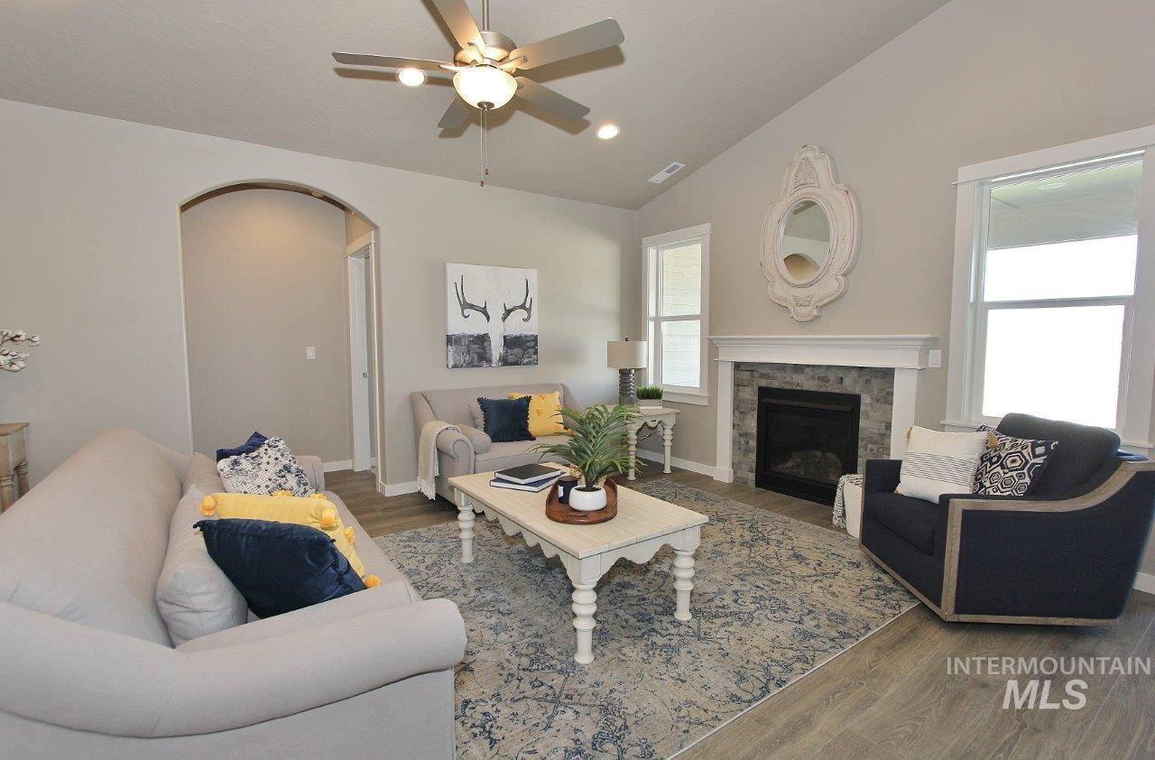3553 North Eleanor Way Star, ID 83669 - Photo 5 of 20 Living room featuring lofted ceiling, wood finished floors, a stone fireplace, arched walkways, and a ceiling fan