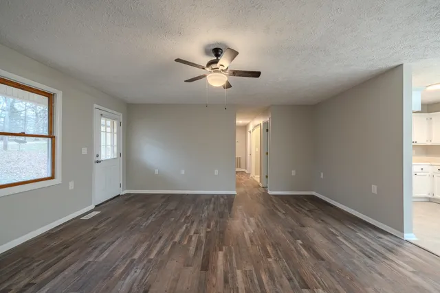a view of an empty room with a window and wooden floor