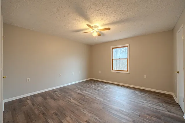 a view of an empty room with window and wooden floor