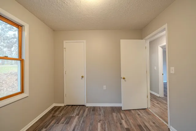 an empty room with wooden floor and windows