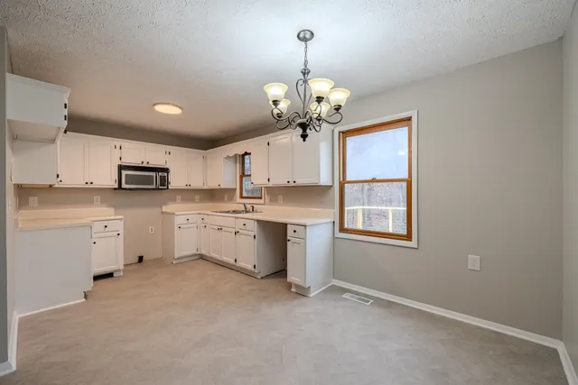 a kitchen with stainless steel appliances granite countertop a stove oven a sink dishwasher and white cabinets with wooden floor