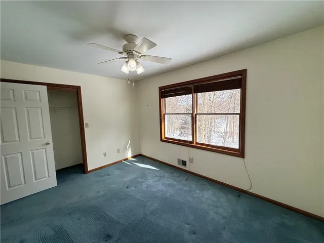 an empty room with chandelier fan and windows