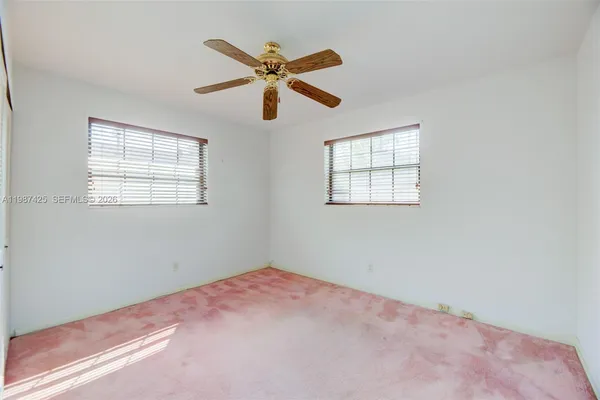 an empty room with a window and a fan