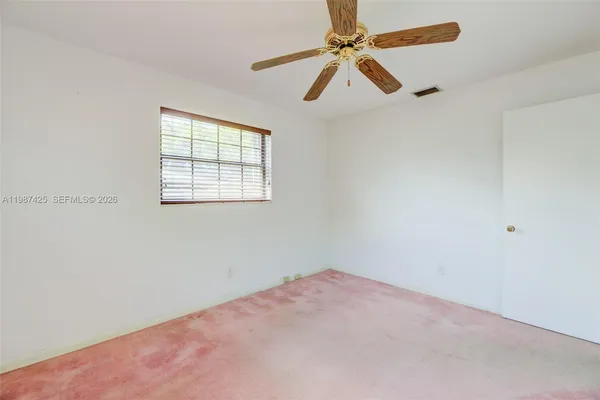 an empty room with a window and a fan