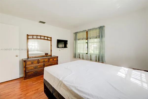 a bedroom with a bed and a flat tv screen on a dresser