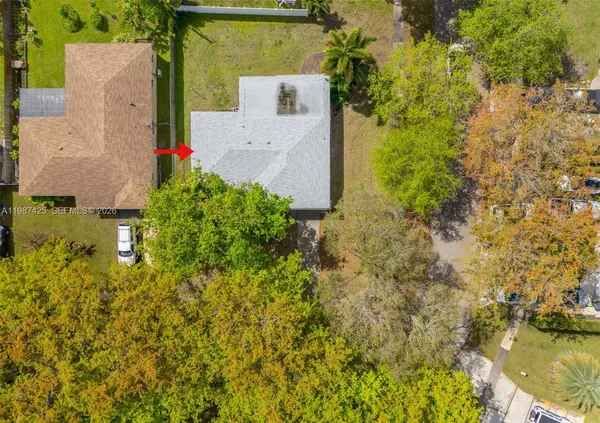 an aerial view of residential house with swimming pool and large trees