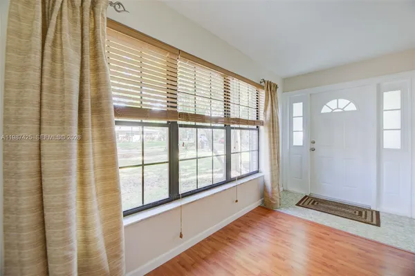 a view of an empty room with wooden floor and a window