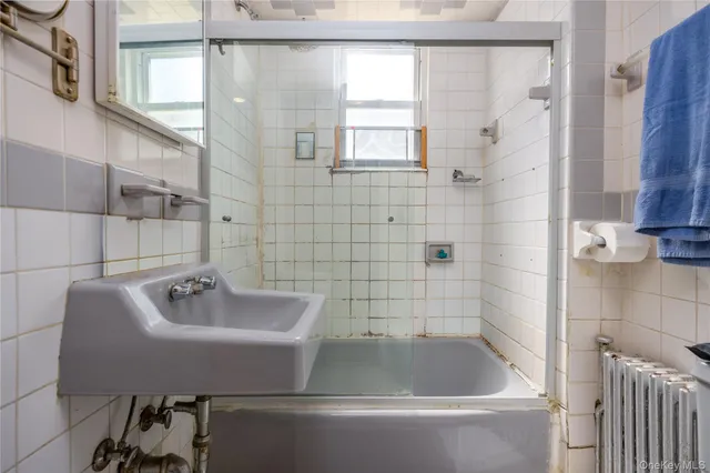 a white bath tub sitting next to a white sink and a shower