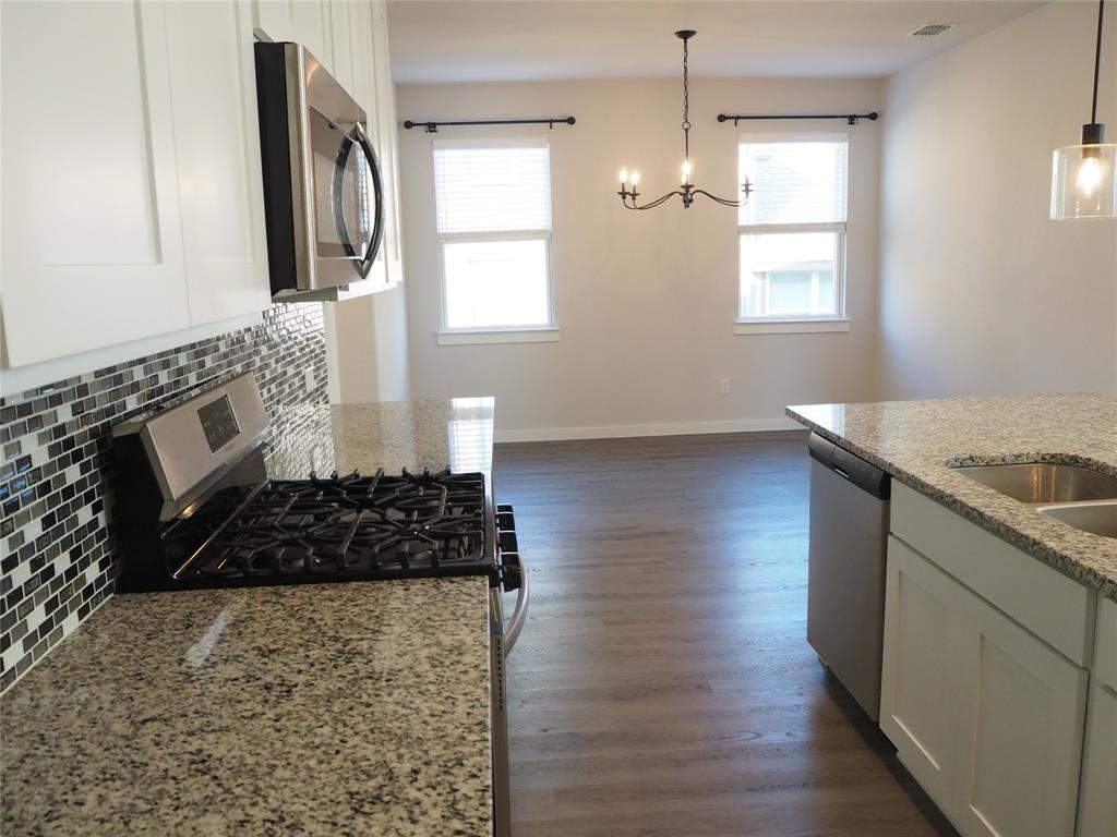 2502 Sun Grove Road Melissa, TX 75454 - Photo 11 of 40 a kitchen with granite countertop a stove a sink wooden floor and a window