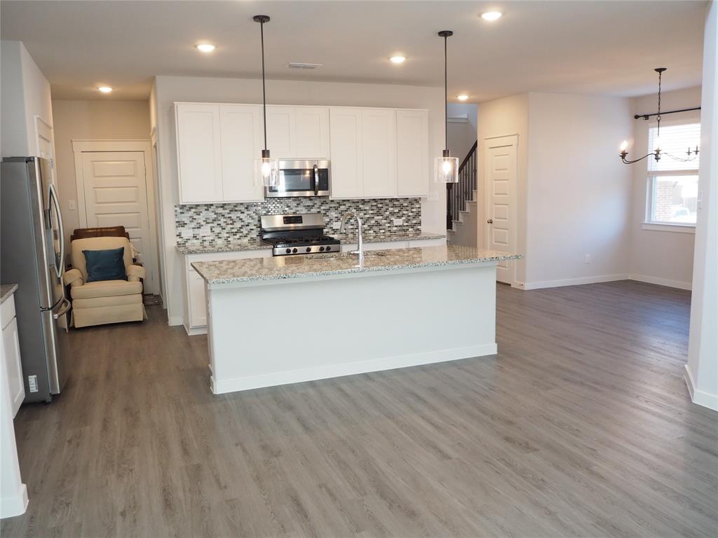 2502 Sun Grove Road Melissa, TX 75454 - Photo 14 of 40 a view of kitchen with stainless steel appliances granite countertop wooden floors and white cabinets