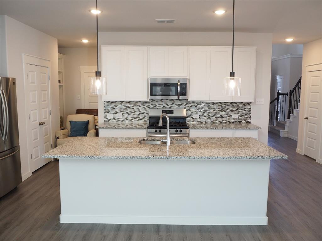 2502 Sun Grove Road Melissa, TX 75454 - Photo 6 of 40 a view of kitchen with stainless steel appliances granite countertop wooden floor white cabinets and a granite counter tops