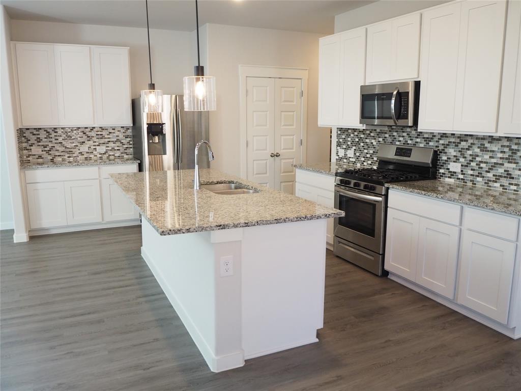 2502 Sun Grove Road Melissa, TX 75454 - Photo 7 of 40 a kitchen with stainless steel appliances kitchen island granite countertop a stove a sink and a microwave