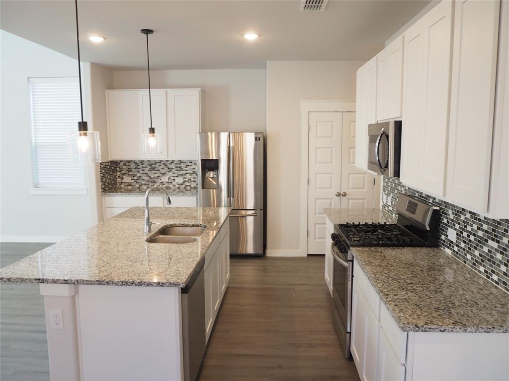 2502 Sun Grove Road Melissa, TX 75454 - Photo 8 of 40 a kitchen with stainless steel appliances granite countertop a sink stove and refrigerator