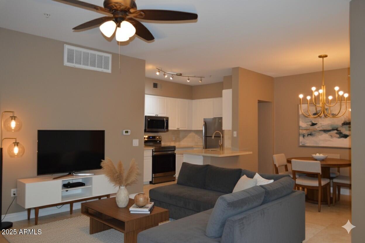 a living room with furniture a chandelier and a flat screen tv