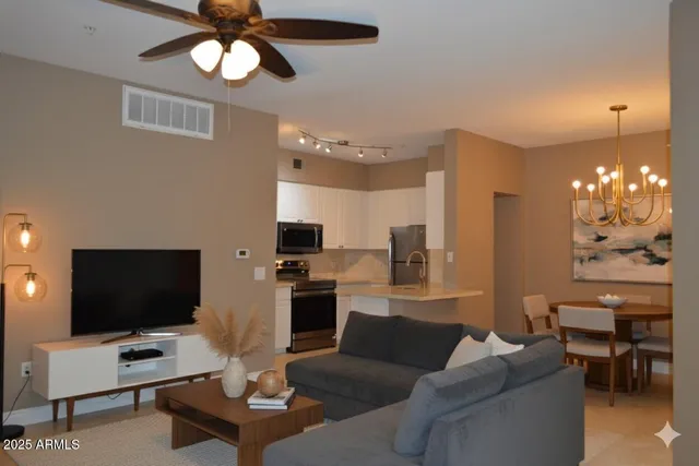 a living room with furniture a chandelier and a flat screen tv
