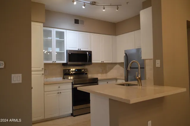a kitchen with kitchen island a sink stainless steel appliances and a counter top space