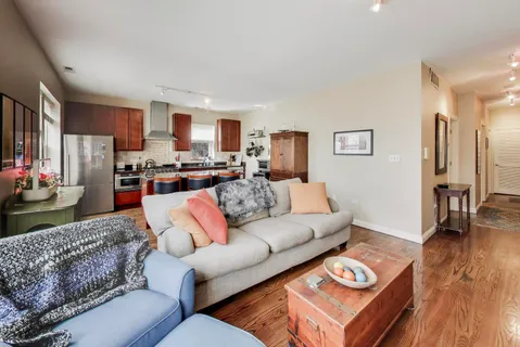 a living room with furniture kitchen view and a wooden floor
