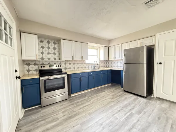 a kitchen with granite countertop a refrigerator stove top oven and sink