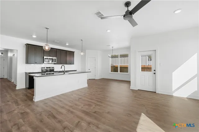 a large kitchen with stainless steel appliances a large counter top a wooden floor a fireplace and a window