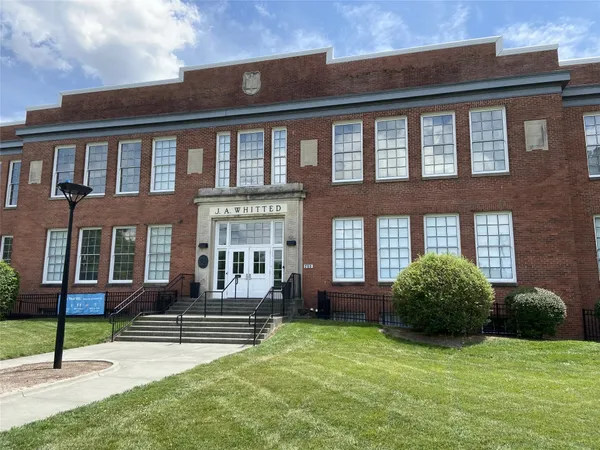 a view of a brick house with a yard and plants