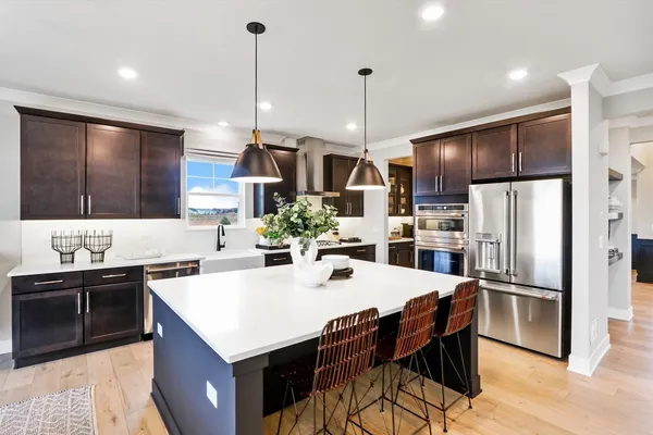 a kitchen with stainless steel appliances kitchen island granite countertop a sink a stove a refrigerator and island with wooden floor