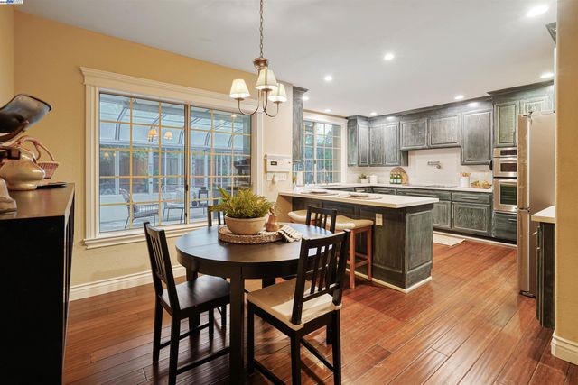 a dining room with stainless steel appliances granite countertop a table chairs and a wooden floor