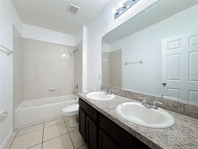a bathroom with a granite countertop sink a toilet a mirror and bathtub