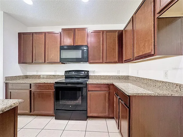 a kitchen with granite countertop a stove top oven microwave and cabinets