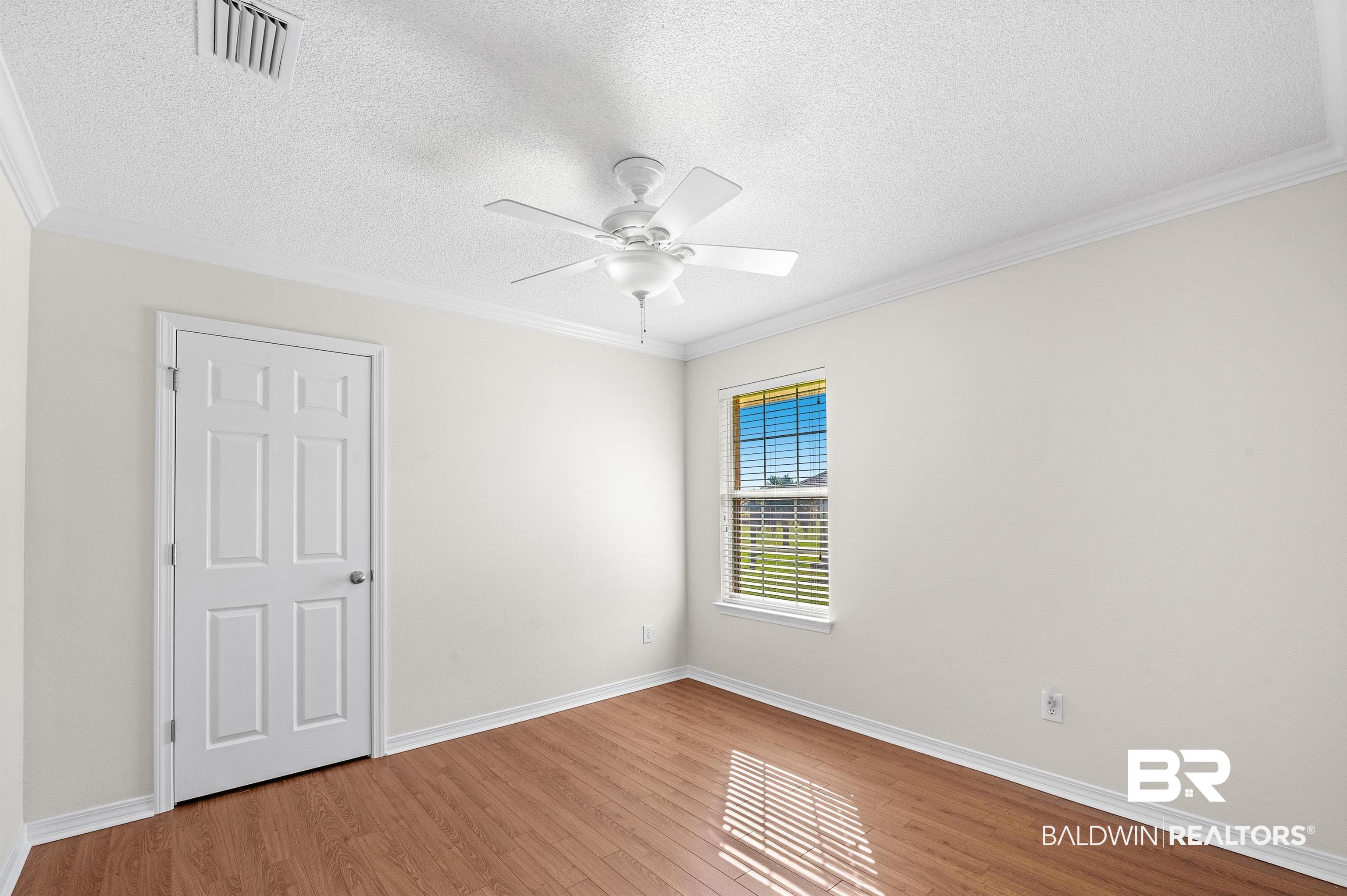 421 Collinwood Loop Foley, AL 36535 - Photo 47 of 62 Empty room with ornamental molding, light hardwood / wood-style flooring, a textured ceiling, and ceiling fan